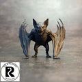 A small dnd miniature bat figurine or toy stands on a gray surface against a smoky gray background. The bat has outstretched wings and an open mouth.