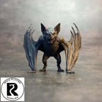 A small dnd miniature bat figurine or toy stands on a gray surface against a smoky gray background. The bat has outstretched wings and an open mouth.