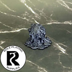 A dnd miniature gray ooze primed in black.

